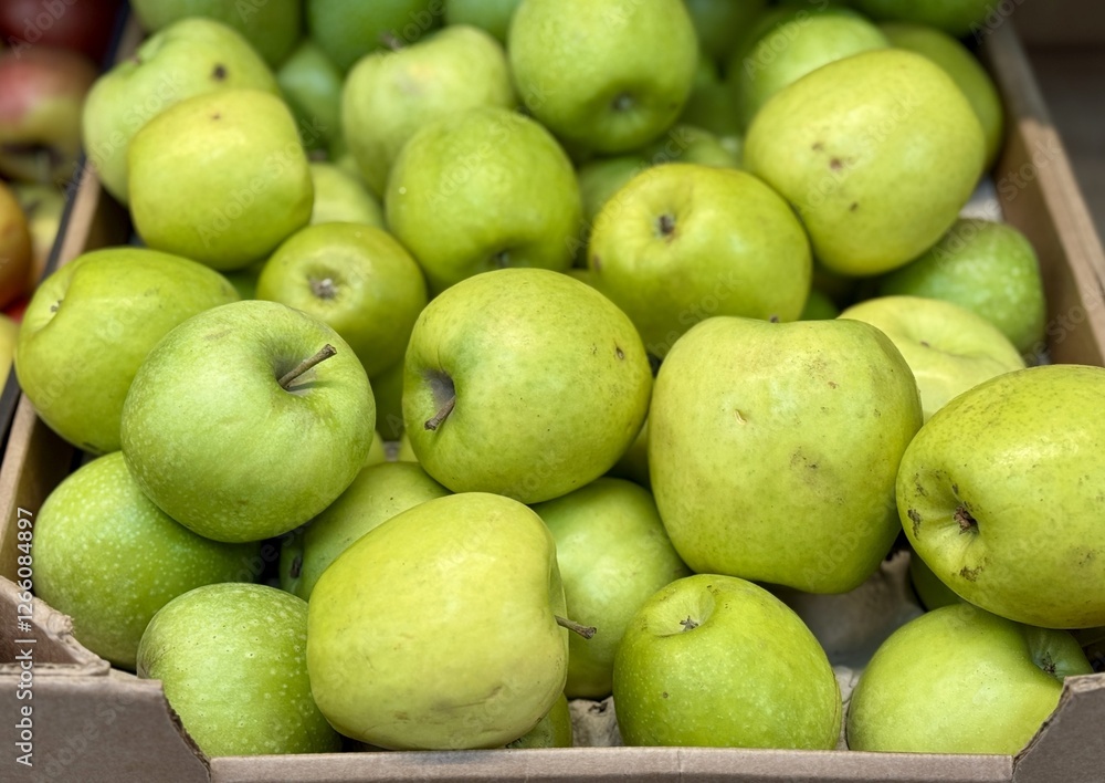 Box filled with fresh natural bio organic green apples placed on counter in local food market. Close-up Box filled with fresh natural bio organic green apples placed on counter in local food market. Close-up