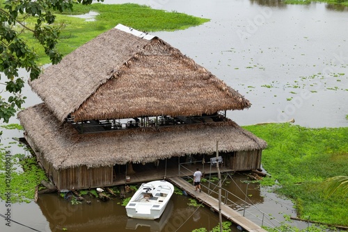 persona no identificada ingresando a una cabaña rustica flotante en la amazonia photo