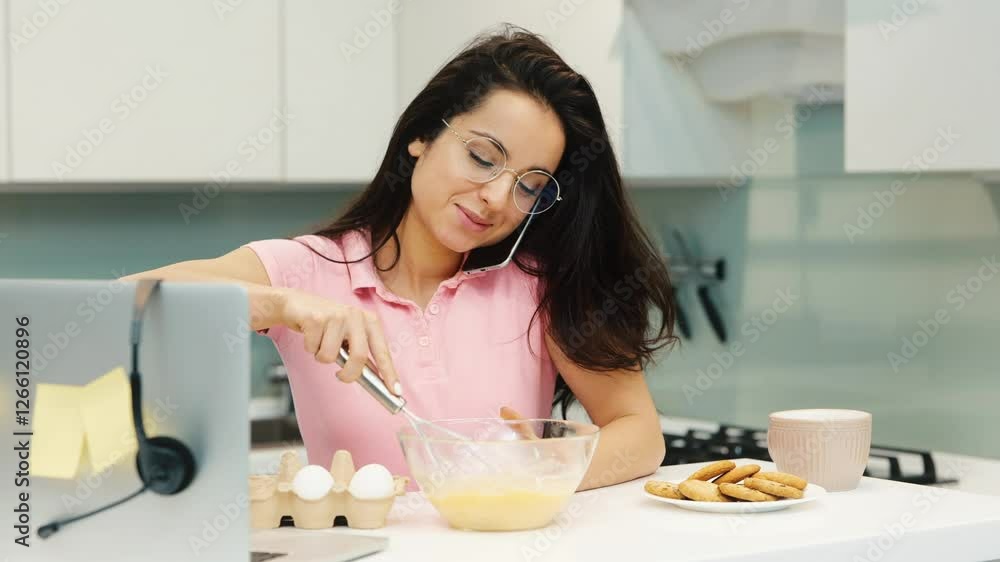 Young woman working at home during quarantine. Slow motion video of girl blending eggs in bowl and talking on phone. Multitasking person in kitchen. Young woman working at home during quarantine. Slow motion video of girl blending eggs in bowl and talking on phone. Multitasking person in kitchen.