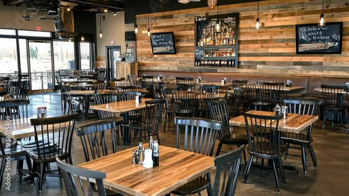 Cozy interior of a restaurant showcasing wooden tables and black chairs in an inviting dining space during daytime