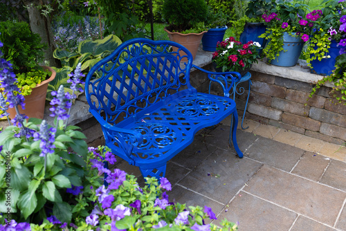 The cobalt blue bench stands freshly transformed, its surface gleaming with a fresh smooth coat of glossy spray paint, inviting visitors to sit and admire the beauty of the vibrant flowers in garden.