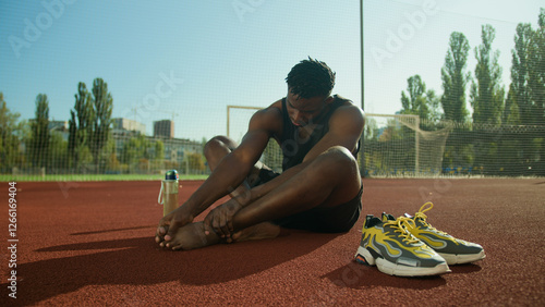 African American man feel ache painful leg pain injured foot after workout outdoors male sportsman footballer guy suffer injury bone finger callus health problem trauma accident on city sport ground photo