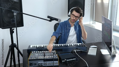 Young man in sound recording studio. Guy in slow motion adjusting music mixing console and listening to it in headphones. photo