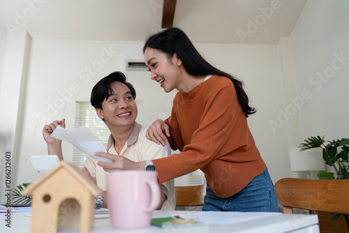 Couple joyfully reviewing financial statements and discussing budgeting strategies at home. photo