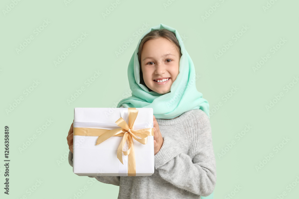 Little Muslim girl with gift on light background Little Muslim girl with gift on light background