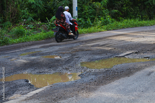 Pothole-ridden road with puddles after rain