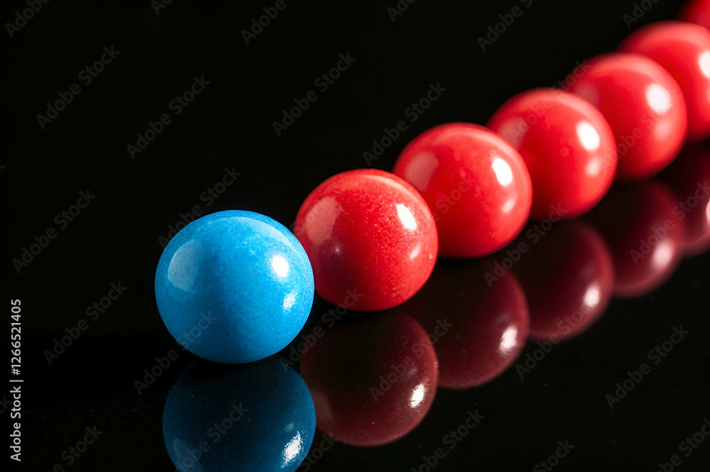 Red Spheres and A Blue Sphere in a Row Reflecting on a Dark Shiny Surface
