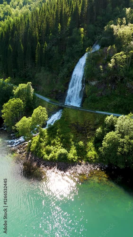 Experience the breathtaking allure of a hidden waterfall cascading down lush green cliffs in Norway. The tranquil waters reflect the vibrant surroundings, Fjaerlandsfjorden Vestland Norway
