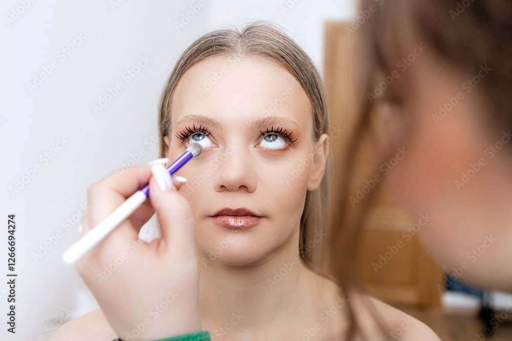 A makeup artist does makeup on a beautiful blonde, paints her eyes with a brush in a beauty salon. Copy space A makeup artist does makeup on a beautiful blonde, paints her eyes with a brush in a beauty salon. Copy space