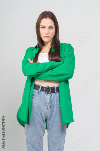 Cute young girl in green shirt and blue jeans posing on a white background