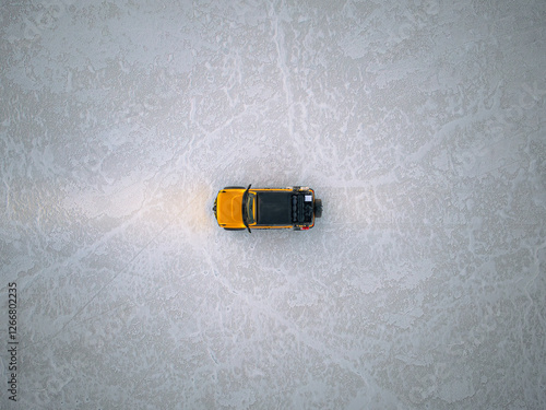 Yellow Truck Driving Across a Salt Flat at Twilight photo