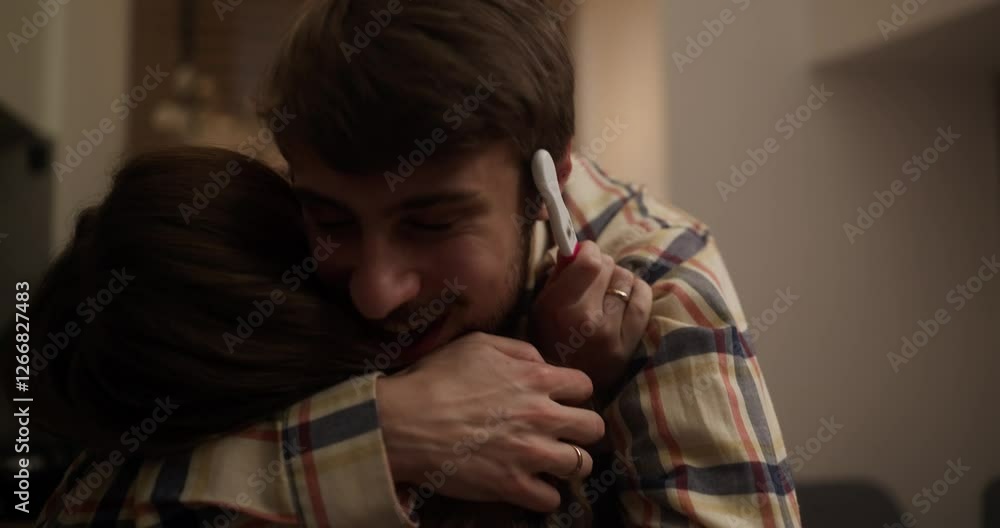 An anxious girl picks up and shows a pregnancy test with two lines to her boyfriend and he hugs her after the good news at home An anxious girl picks up and shows a pregnancy test with two lines to her boyfriend and he hugs her after the good news at home