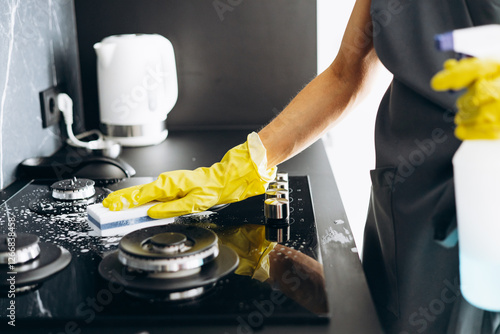 Bild auf Leinwand Woman housekeeper cleaning stove surface