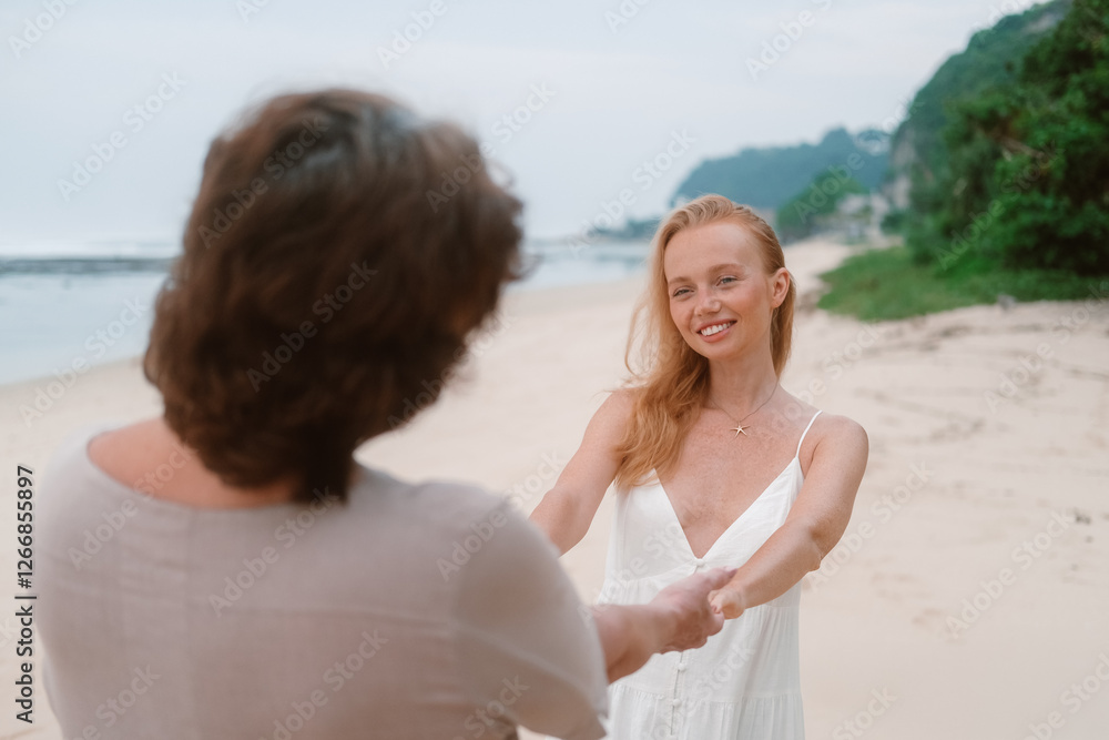 A young red haired woman holds her senior mother hands and looks at her with a smile and care. They are standing on the beach near the ocean. Family vacation. Mothers Day. A young red haired woman holds her senior mother hands and looks at her with a smile and care. They are standing on the beach near the ocean. Family vacation. Mothers Day.