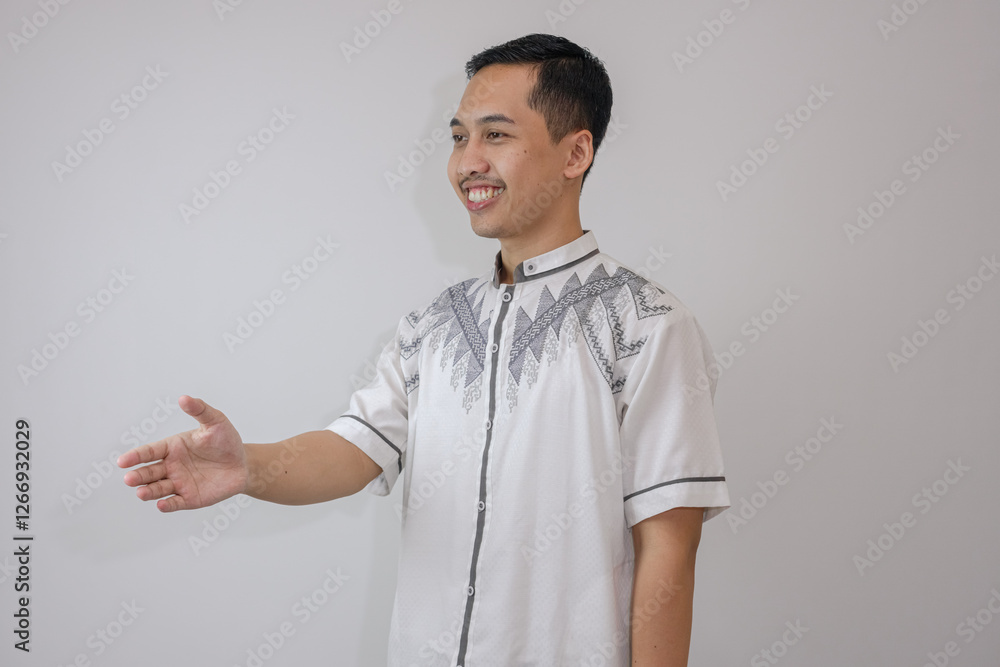 Isolated Muslim Man Wearing White Clothes Offering a Handshake Gesture While Facing to the Side, Standing Alone With a Friendly Expression. Isolated Muslim Man Wearing White Clothes Offering a Handshake Gesture While Facing to the Side, Standing Alone With a Friendly Expression.