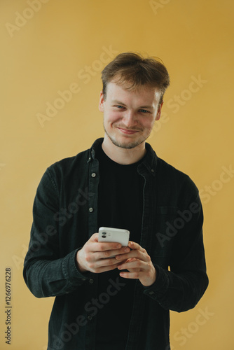 Wallpaper Mural Young Smiling Man Using Smartphone Against Yellow Background Torontodigital.ca