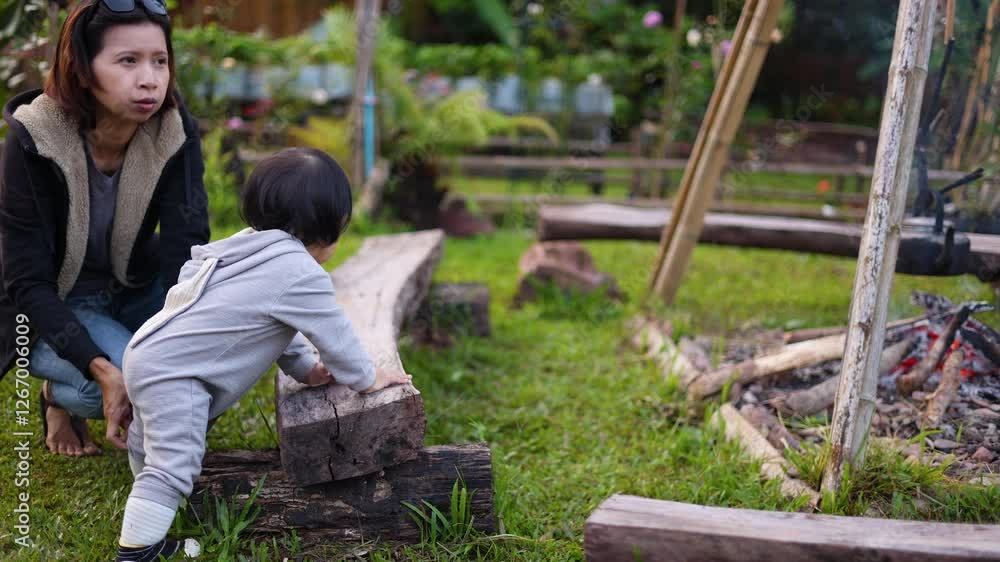 A toddler tries to climb on the log. A toddler tries to climb on the log.