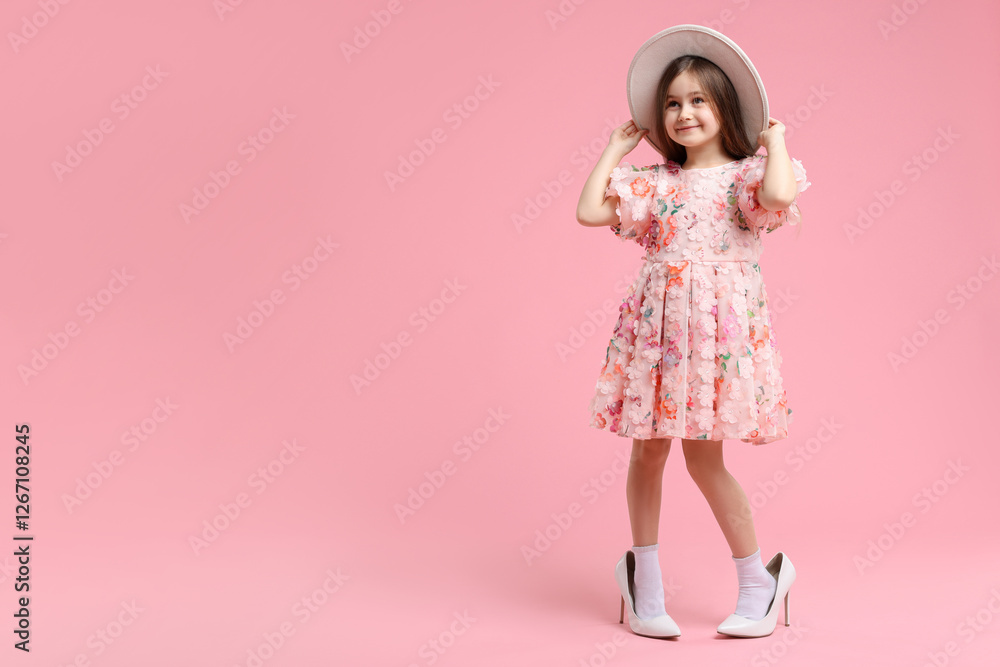 Stylish little girl wearing oversized high heeled shoes on pink background, space for text Stylish little girl wearing oversized high heeled shoes on pink background, space for text