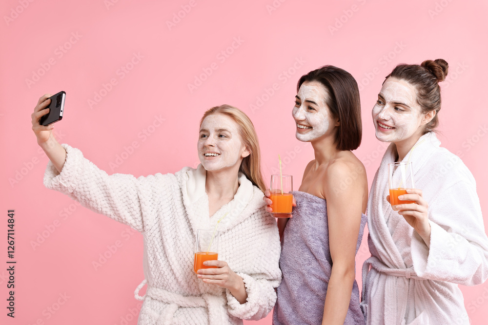 Spa day. Beautiful women with face masks and healthy drinks taking selfie on pink background Spa day. Beautiful women with face masks and healthy drinks taking selfie on pink background