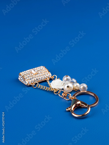 close up of beautiful shiny white rhinestone handbag keychain on blue background photo