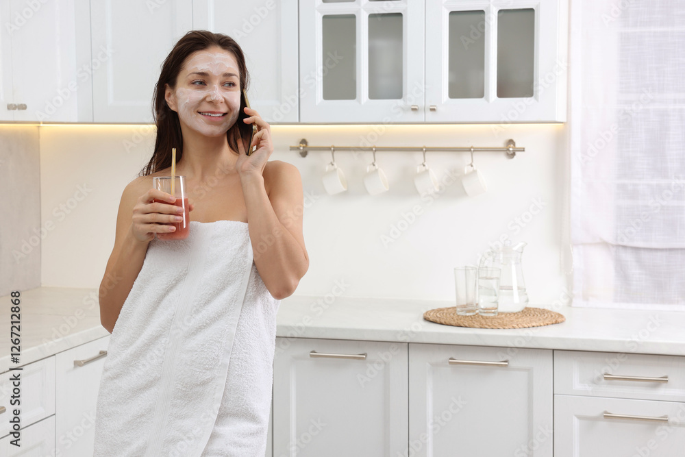 Spa day. Beautiful woman with face mask and juice talking on smartphone in kitchen, space for text Spa day. Beautiful woman with face mask and juice talking on smartphone in kitchen, space for text
