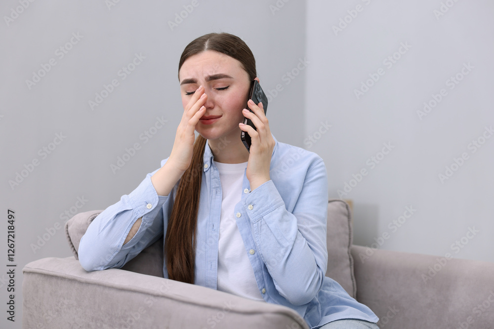 Stressed woman calling hotline for mental health help in armchair at home Stressed woman calling hotline for mental health help in armchair at home