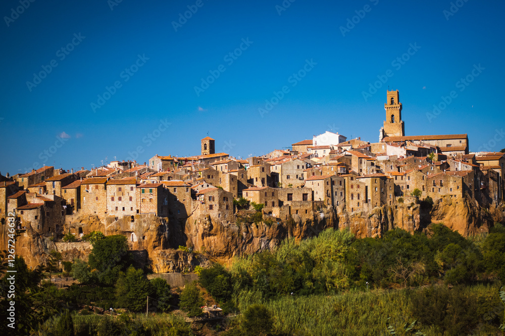 Scenic view to th city of Pitigliano standing on the rocks and dominating the Tuscany landscape invites you to discover this jewell also called second Matera. Scenic view to th city of Pitigliano standing on the rocks and dominating the Tuscany landscape invites you to discover this jewell also called second Matera.