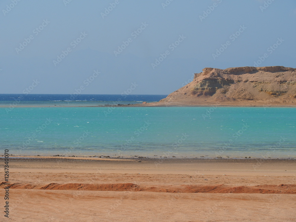 A stunning turquoise pool of water contrasts against a rugged, rocky shoreline and a clear blue sky in Saudi Arabia. The scene offers a serene and picturesque view of the Red Sea coast. A stunning turquoise pool of water contrasts against a rugged, rocky shoreline and a clear blue sky in Saudi Arabia. The scene offers a serene and picturesque view of the Red Sea coast.