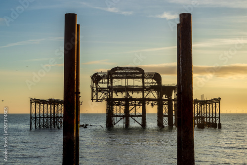 A view of the remains on West Pier in Brighton, with a sunset sky behind photo