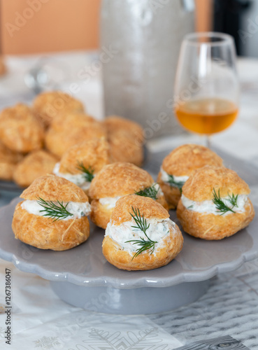 A traditional French savory choux dough cheese puff stuffed with fresh cheese mixed with smoked salmon and dill leaves, glass of cider in background. Pastry well know as specialty of Burgundy  photo