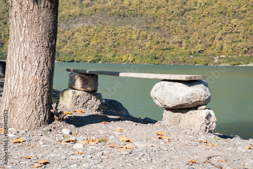 Canvastavla Unique stone bench by the river with a serene view of nature in autumn