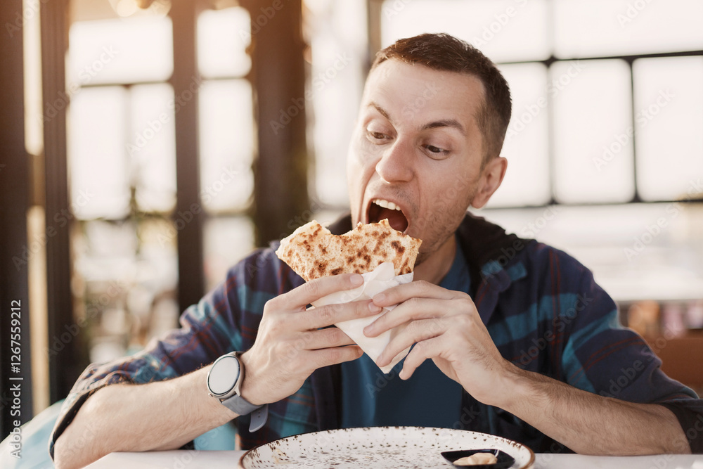 Young man savoring a delicious sweet crepe while seated at a restaurant table, enjoying the flavors of casual dining during lunchtime