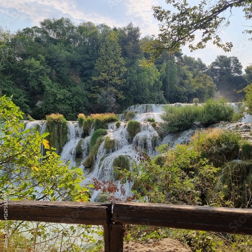 Cascading waterfalls flowing over mossy rocks, framed by lush green trees and foliage. Peaceful and serene natural scene. Ideal for nature, travel, or background use.  Krka National Park, Croatia.