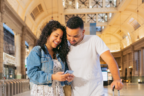 latin couple men and women inside a transportation station check the phone looking for information