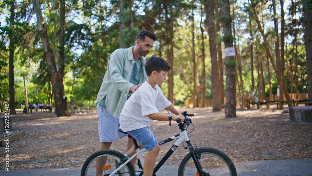 Daddy teaching son riding bicycle sunny forest. Active father child having fun Daddy teaching son riding bicycle sunny forest. Active father child having fun