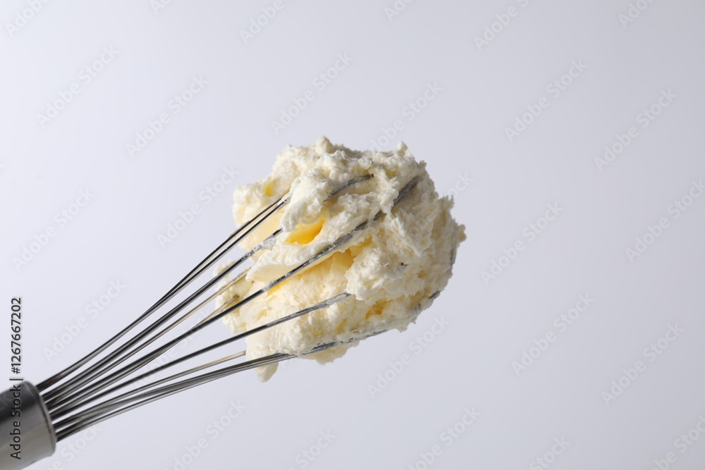 Fototapeta premium Whisk with whipped cream on white background, closeup. Space for text