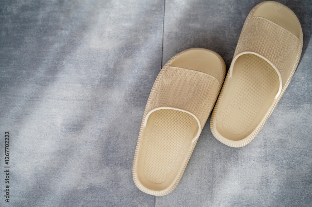 one pair of beige rubber slippers stand on the gray granite floor one pair of beige rubber slippers stand on the gray granite floor