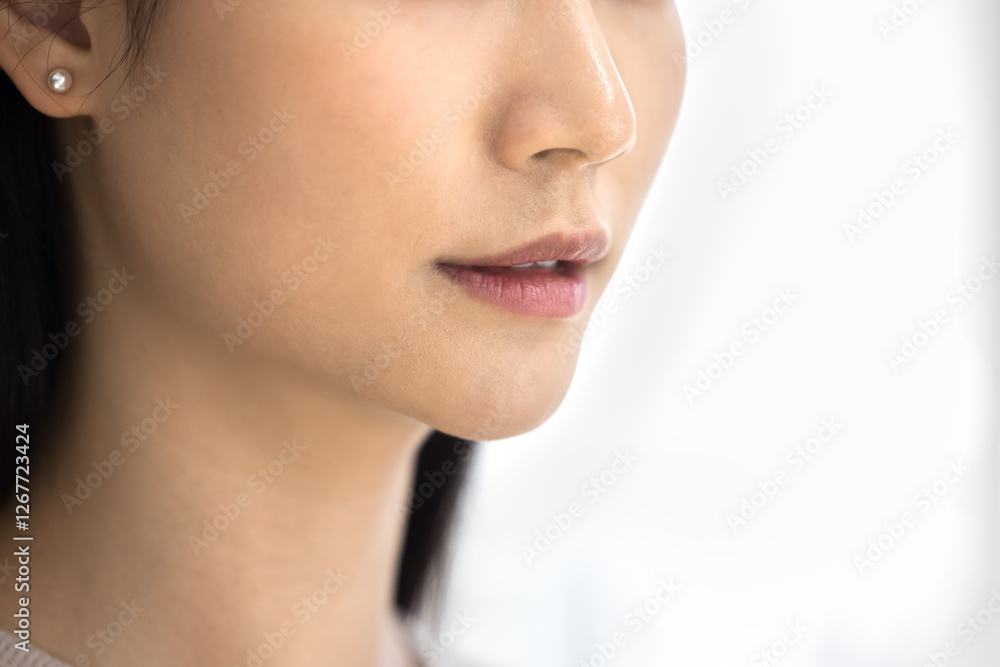 Close up shot of young beautiful Asian womans lower face with smooth, perfect skin, focus on her lips and jawline, copy space background view. Elegance, natural beauty, cosmetology, lip augmentation Close up shot of young beautiful Asian womans lower face with smooth, perfect skin, focus on her lips and jawline, copy space background view. Elegance, natural beauty, cosmetology, lip augmentation