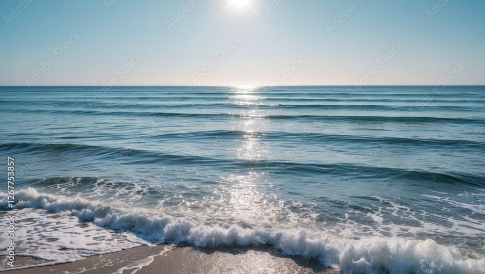 Calm ocean waves under bright sun with clear blue sky and sandy beach in foreground Copy Space Calm ocean waves under bright sun with clear blue sky and sandy beach in foreground Copy Space