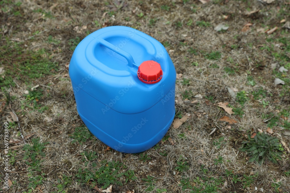 One blue plastic canister on ground outdoors One blue plastic canister on ground outdoors