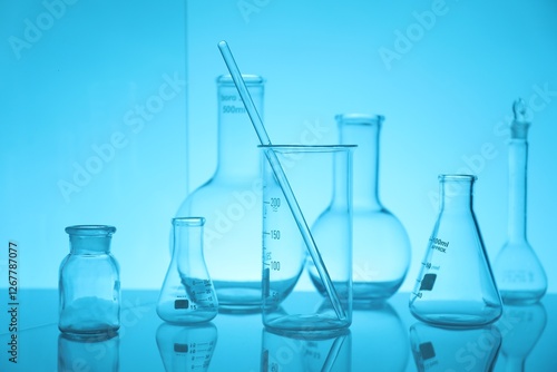 Laboratory glassware on mirror surface against light blue background