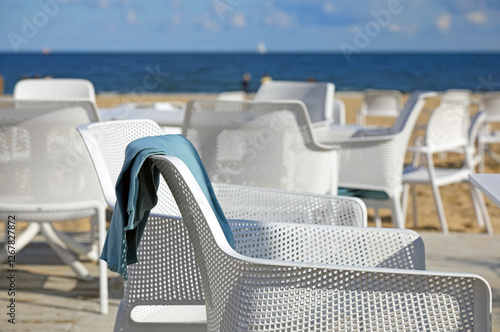 Fototapeta Naklejka Na Ścianę i Meble -  Blanket on the back of an empty seat of an outdoor cafe on a beach in the city of Sopot, Poland