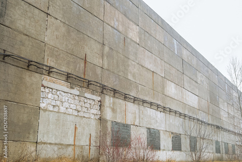 Old worn out facade of a long multi-span industrial building workshop. Wall made of unprotected reinforced concrete wall slabs. Soviet industrial building. photo