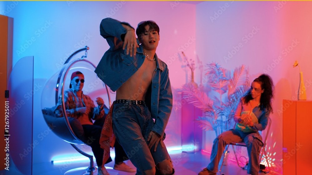 Fototapeta premium Skilled asian dancer moving to modern music while multicultural friend sitting at chair. Professional performer dancing show energetic foot step while hipster team cheering and supporting. Regalement.