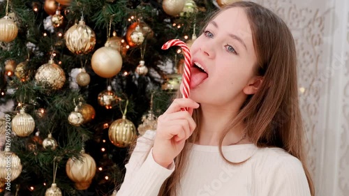A young woman licks a Christmas candy lollipop.