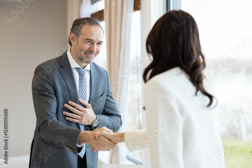 Konstfotografi A man and woman engage in a professional handshake, symbolizing agreement and collaboration in a modern office setting