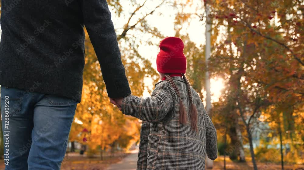 Small girl with long braids enjoys autumn atmosphere with father during stroll. Caring father takes cute girl for walk holding hand. Loving father with girl relish warm sunshine and fresh air in park Small girl with long braids enjoys autumn atmosphere with father during stroll. Caring father takes cute girl for walk holding hand. Loving father with girl relish warm sunshine and fresh air in park