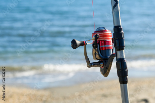 Surfcasting fishing rod standing on the beach, showing reel detail