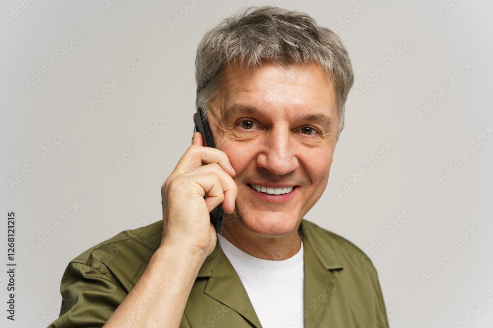 Man smiling while talking on a smartphone in a well-lit indoor setting with neutral background Man smiling while talking on a smartphone in a well-lit indoor setting with neutral background