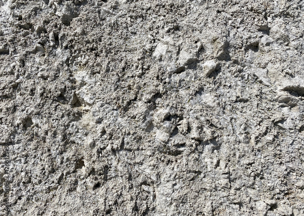 The image is a close-up of a textured surface. The surface appears to be made up of small, irregularly shaped rocks or stones. The colors of the rocks vary The image is a close-up of a textured surface. The surface appears to be made up of small, irregularly shaped rocks or stones. The colors of the rocks vary